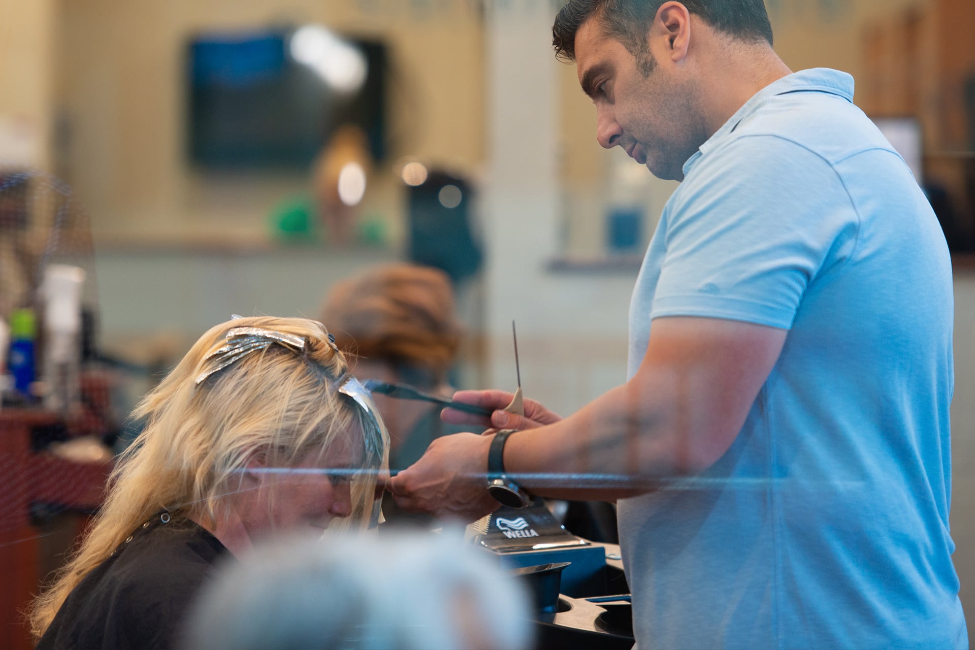 Man dyes woman's hair blonde in salon