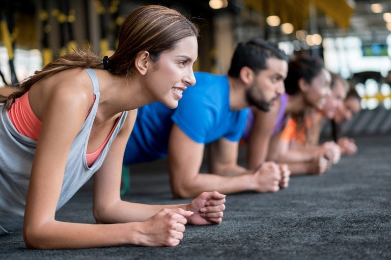 Diverse group of people plank in a gym class studio