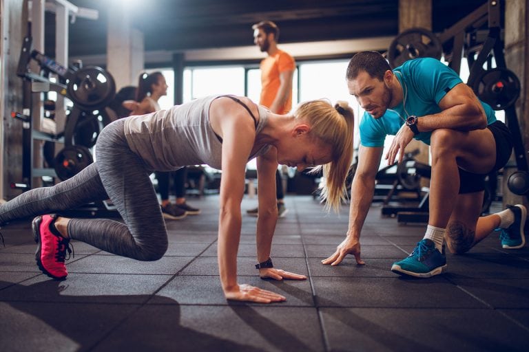 Male personal trainer encourages woman while she exercises