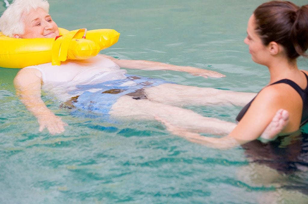 female aquatics therapist working with a woman using a neck float