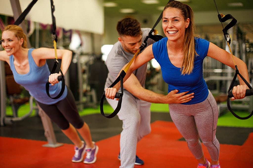 personal trainer shwowing a woman how to properly use the TRX rings