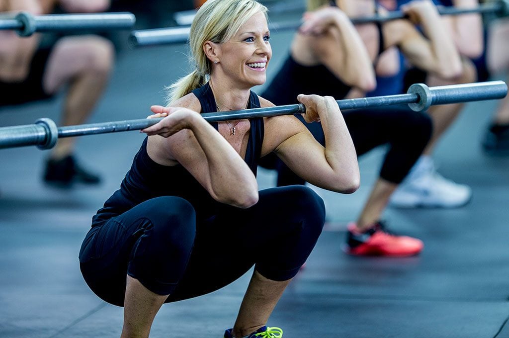woman lifting a weight bar in a group fitness class