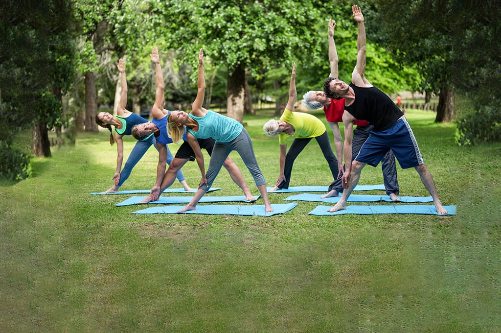 group of people stretching on yoga mats outdoors