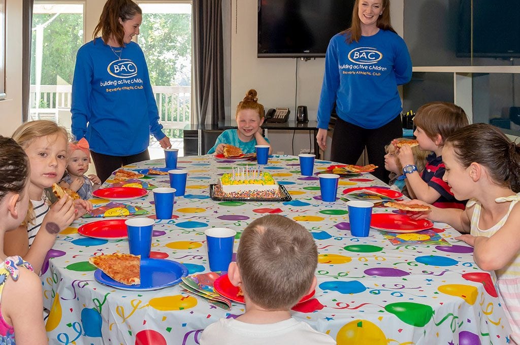 kids at a birthday party table eating pizza