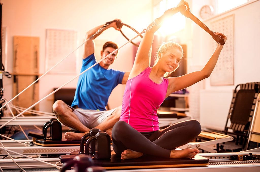 man and woman working out on a pilates reformer machine