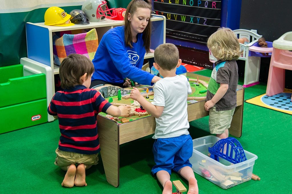teacher at childcare facility at gym, playing with children