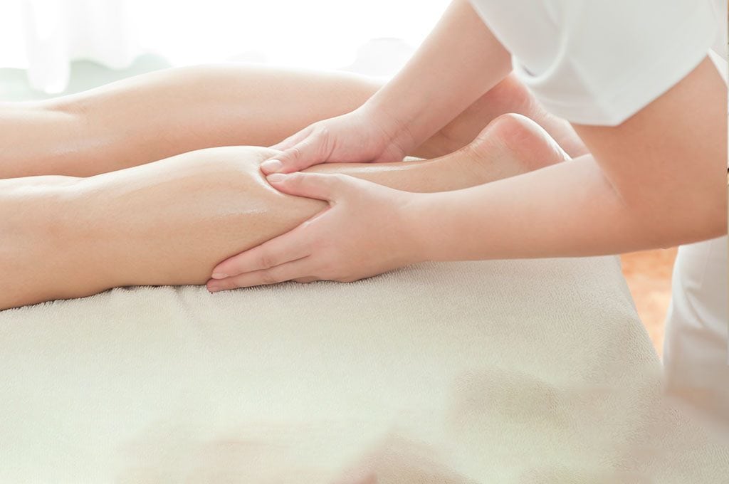female massage therapist massaging a woman's leg
