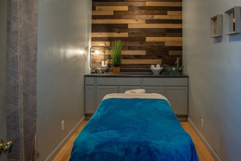 serene massage room with bamboo wall and blue velvet massage table