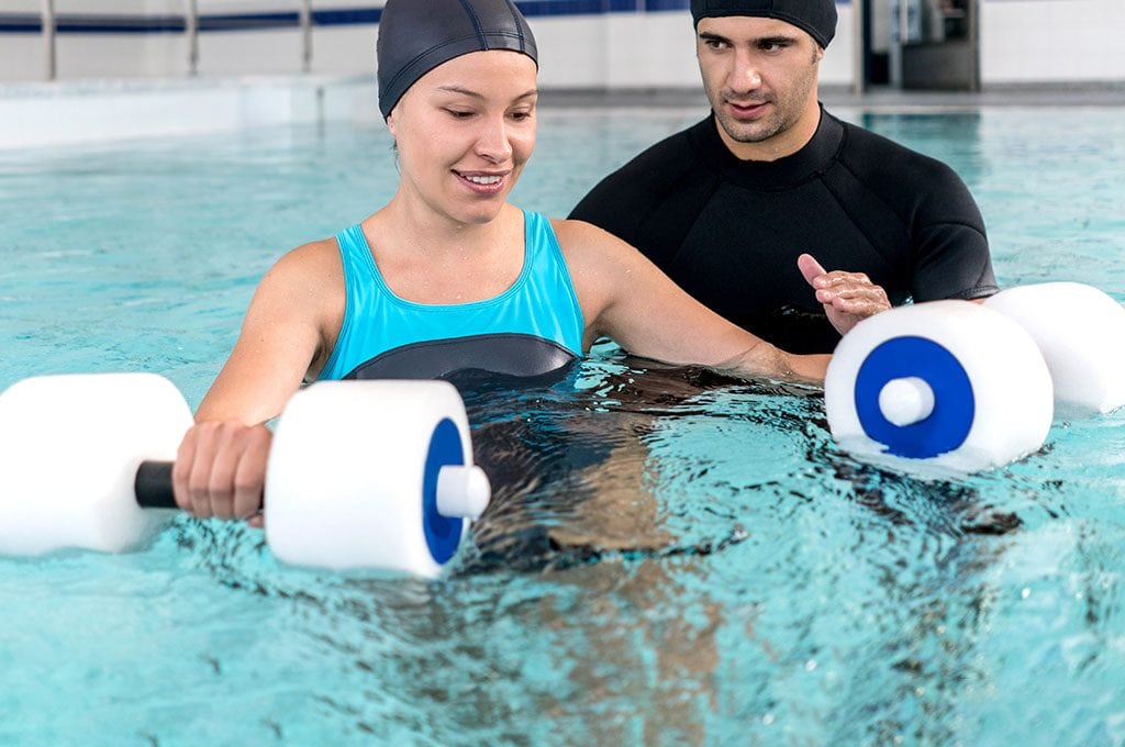 male hysical therapist helping a woman with water weights