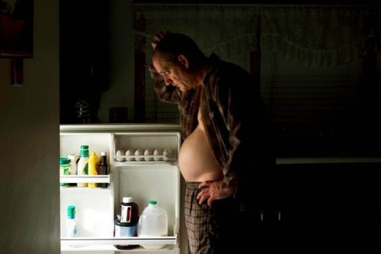 over weight man looking in the fridge for food in the middle of the night