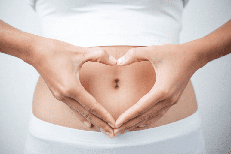 women with her hands in the front of her stomach her hands are in the shape of a heart