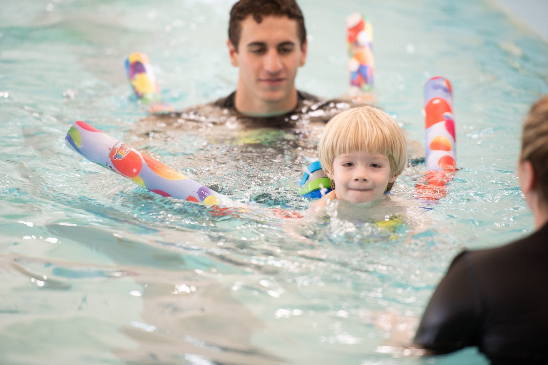 child in pool receiving swim lessons from beverly gym swim instructor